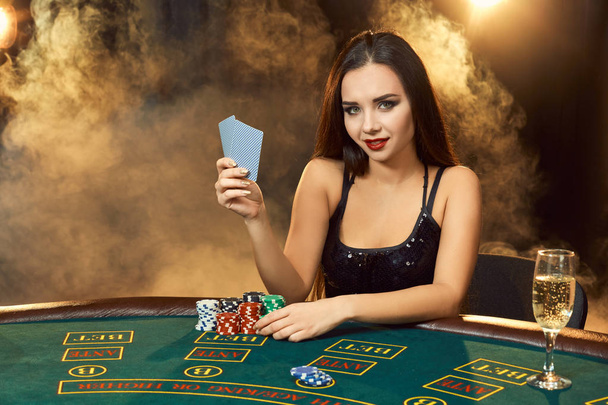 Gorgeous young woman sitting at poker table with glass of champagne - Foto, immagini