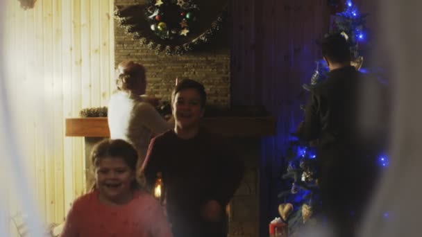Cheerful family looking through window in Christmas night - Filmati, video
