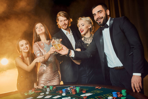Grupo de personas felices durante la celebración está bebiendo vino espumoso en el casino
 - Foto, imagen