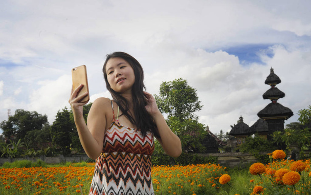 молодий китайський азіатських туристичних жінка приймає Автопортрет selfie фото з мобільного телефону через красиві квіти поле краєвид подорож - Фото, зображення