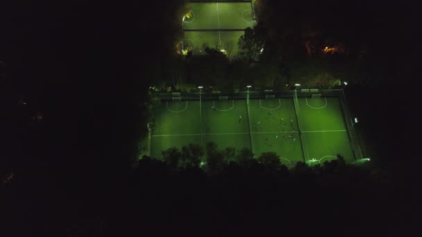 Luftaufnahme des Fußballplatzes bei Nacht mit Amateurfußballern, die das Spiel in der Stadt spielen. Clip. Fußballplatz Nacht Antenne - Filmmaterial, Video