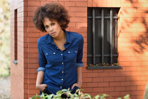 Joven mujer negra con peinado afro de pie en el fondo urbano
 - Foto, Imagen