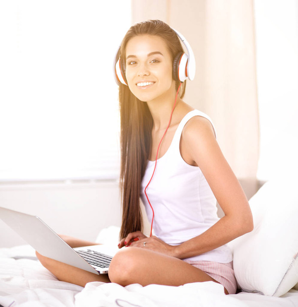 Giovane bella donna a letto ad ascoltare musica
 - Foto, immagini