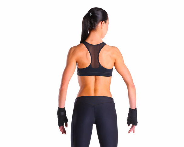 Мускулистая молодая женщина позирует в спортивной одежде на черном фоне
 - Фото, изображение