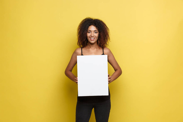 Business Concept - Close up Ritratto giovane bella attraente afroamericano sorridente mostrando semplice segno bianco vuoto. Yellow Pastel studio di sfondo. Copia spazio
 - Foto, immagini