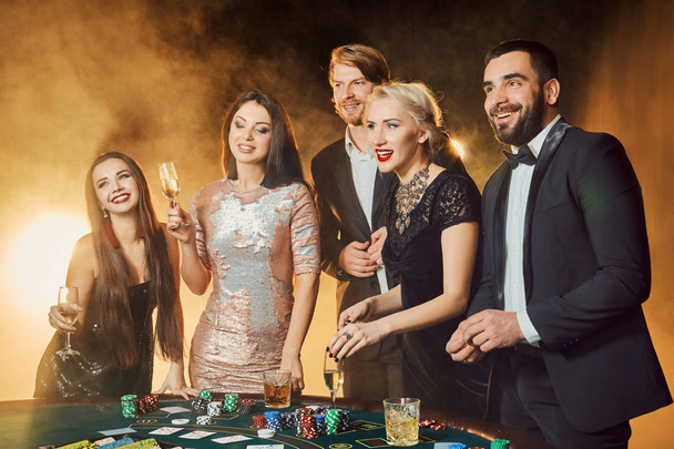 Gruppe fröhlicher Menschen während der Feier trinkt Sekt im Casino - Foto, Bild