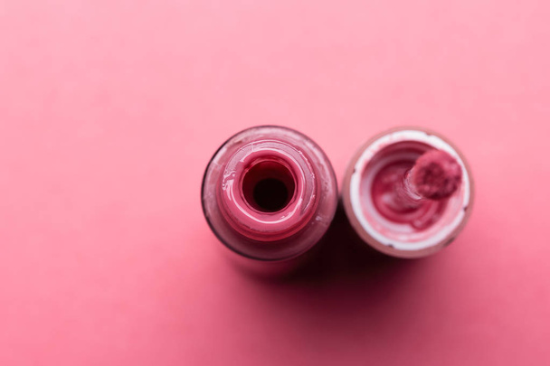 Cepillo para labios de maquillaje y la botella de lápiz labial líquido de cerca sobre un fondo rosa con espacio para copiar - Foto, imagen