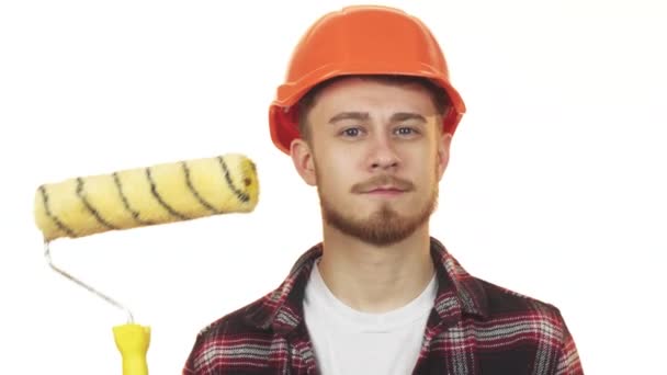 Szczęśliwy młody mężczyzna konstruktora trzymając wałek malarski, Wyświetlono: kciuk - Materiał filmowy, wideo