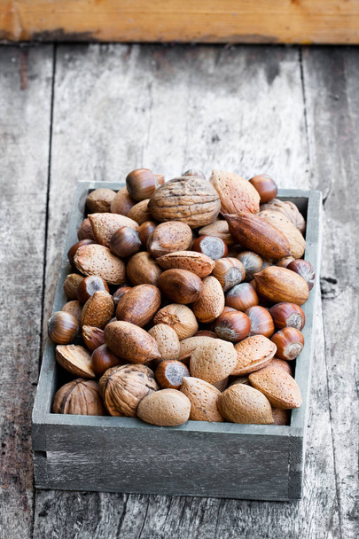 Various  nuts in wooden box on rustic table  - Fotó, kép