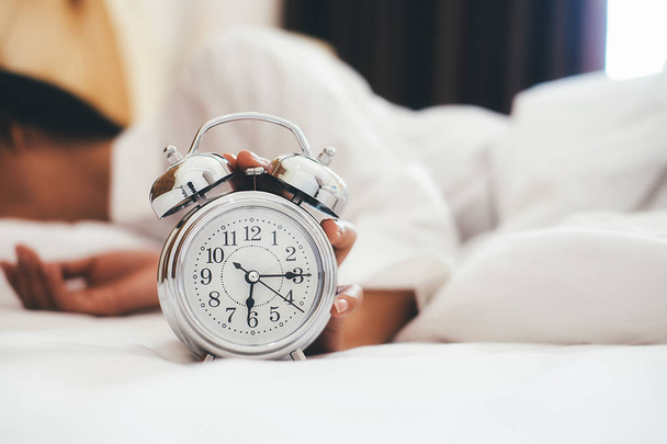 Mujer joven irritada apagando su despertador por la mañana
 - Foto, Imagen