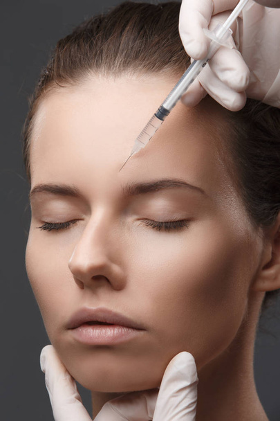 Portret van een jonge blanke vrouw die een cosmetische injectie krijgt - Foto, afbeelding