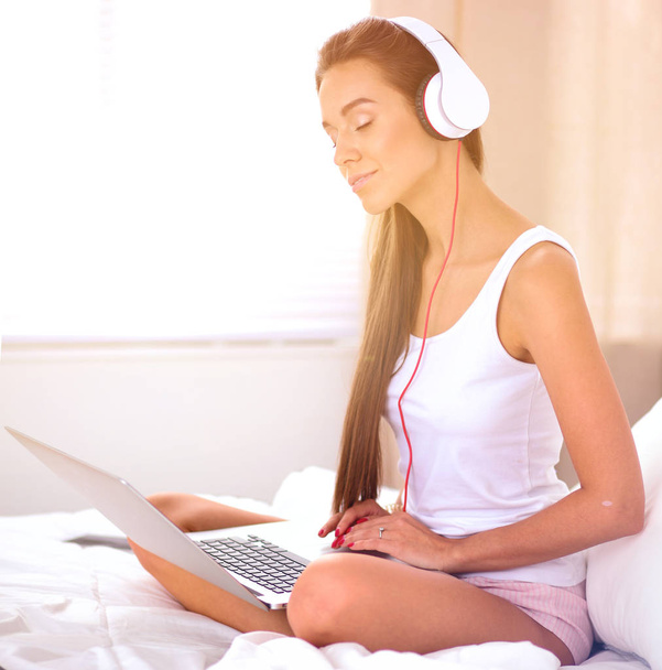 Nuori kaunis nainen sängyssä kuuntelemassa musiikkia
 - Valokuva, kuva