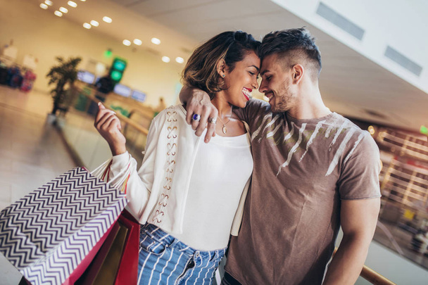Jovem casal feliz olhando uns aos outros depois de fazer compras segurando um sacos
 - Foto, Imagem