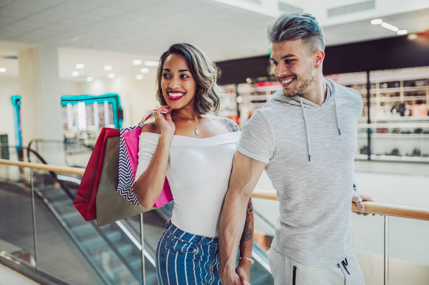  Szczęśliwa Młoda para z torby na zakupy spaceru w centrum handlowym - sprzedaż, koncepcja konsumpcjonizm i osób  - Zdjęcie, obraz