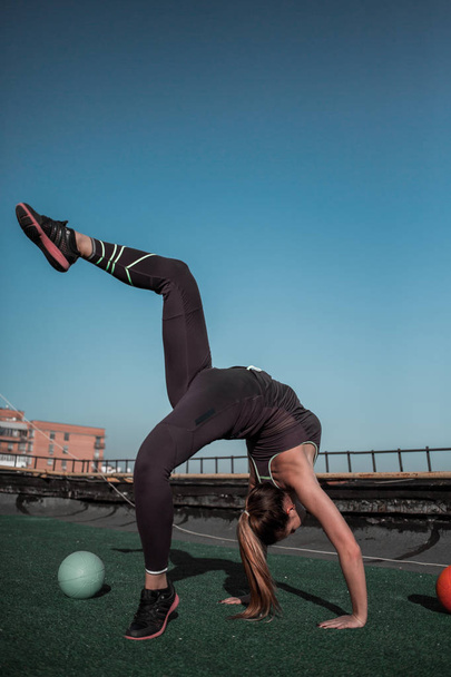 Beautiful gymnast woman training on the roof of the building. - Foto, Imagen