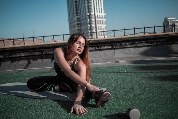 Fitness on the roof, sporty girl doing stretching. - Foto, Imagen