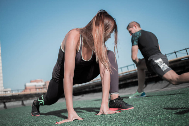 Sportive man and woman doing lunges outdoors. - Photo, image