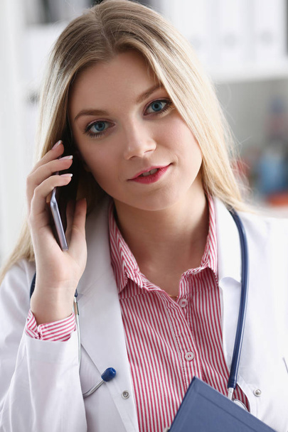 Beautiful female blond doctor talking on phone - Foto, Imagen