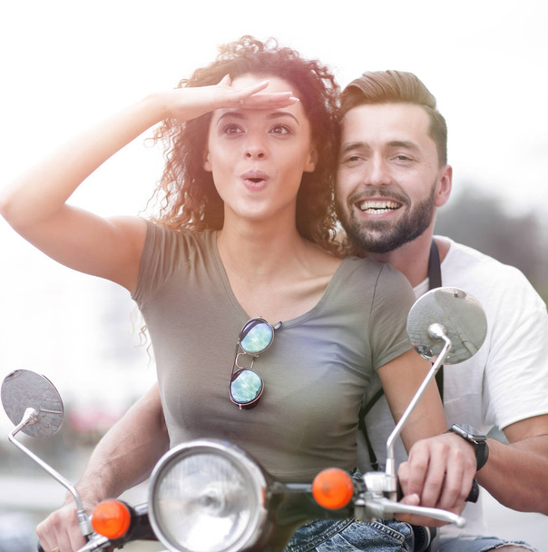Beautiful young couple is smiling while riding a scooter - Foto, imagen