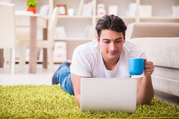 Man working on laptop at home on carpet floor - Foto, immagini