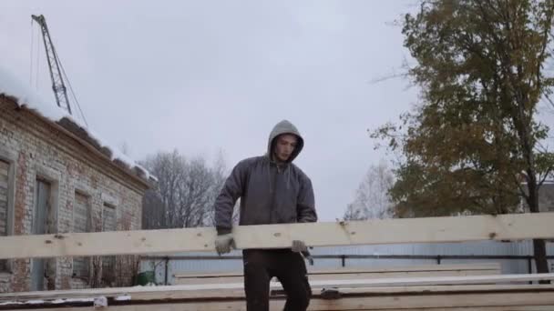 Αχθοφόρος μεταφέρουν ξύλινη σανίδα στο εργοστάσιο κορμοπλατεία χειμερινή ημέρα - Πλάνα, βίντεο