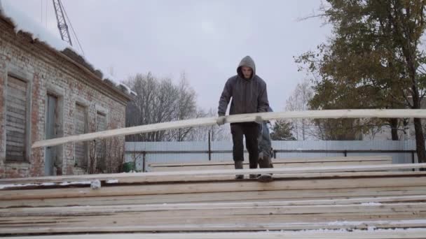 冬の日の製材工場のヤードで木板を運ぶ持ち上げる人 - 映像、動画