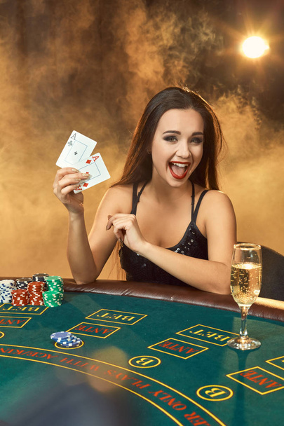 Прекрасная молодая женщина сидит за покерным столом с бокалом шампанского
 - Фото, изображение