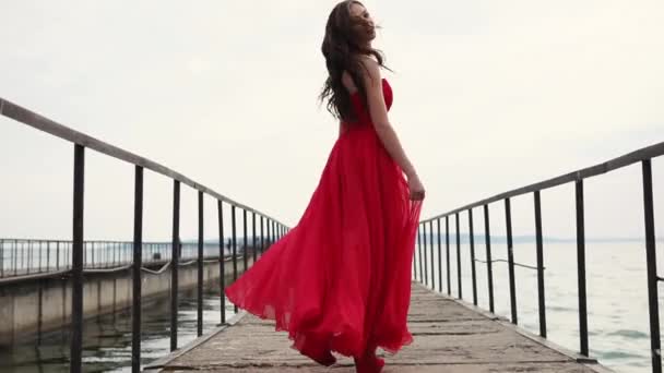 donna sorridente spensierata sta camminando sul molo, agitando il suo abito rosso seta
 - Filmati, video