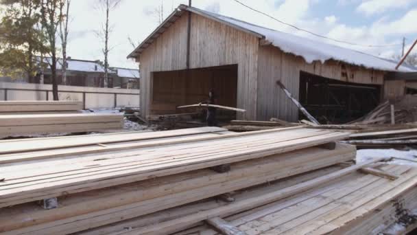 Mann arbeitet an Packungen voll gepackter Holzbretter, die im Hof eines Sägewerks gelagert sind - Filmmaterial, Video