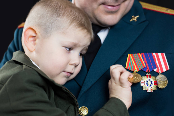 A small boy in military uniform looks at military medals. - Foto, Bild