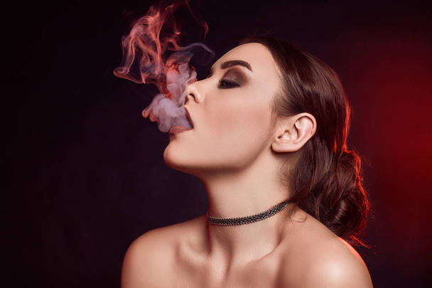 Αίγλη σαγηνευτική πανέμορφη μελαχρινή γυναίκα καπνίζοντες ηλεκτρονικό τσιγάρο - Φωτογραφία, εικόνα