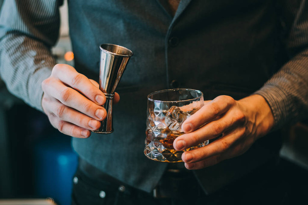 Barman výrobu alkoholických koktejlů, kovové štamprle a bar prostředí - Fotografie, Obrázek