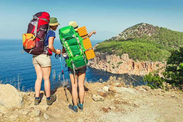 Deux randonneurs avec des sacs à dos regardant la mer depuis le sommet d'une montagne
 - Photo, image