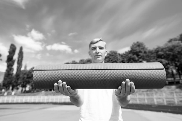 fitness mat blue color in hands of sport man - Photo, Image