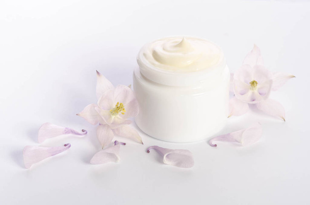 Cute flowers and petal and a jar of natural body cream  - Photo, image