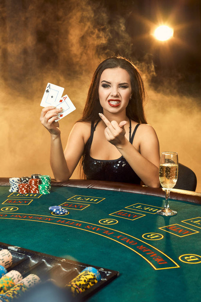 Gorgeous young woman sitting at poker table with glass of champagne - Photo, Image