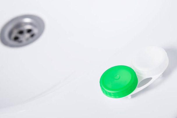 un recipiente para el almacenamiento de lentes se encuentra en un lavabo blanco
 - Foto, imagen