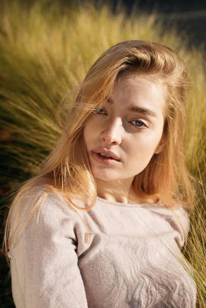 szép fiatal szőke modell lány ül a fűben, a nap és a jelent - Fotó, kép