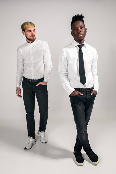Koncepce mezinárodní přátelství. Studio záběr ze dvou stylových mladých mužů na bílém pozadí - Fotografie, Obrázek