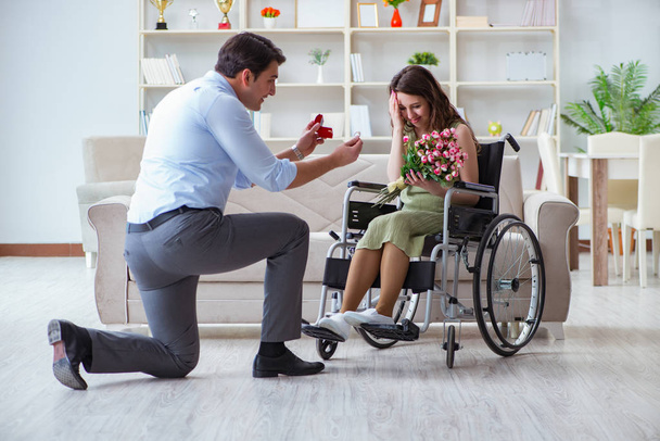 Hombre haciendo propuesta de matrimonio a mujer discapacitada en silla de ruedas - Foto, imagen
