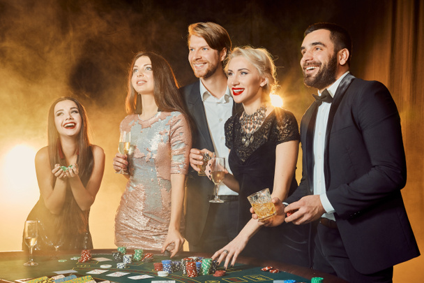 Grupo de personas felices durante la celebración está bebiendo vino espumoso en el casino
 - Foto, imagen