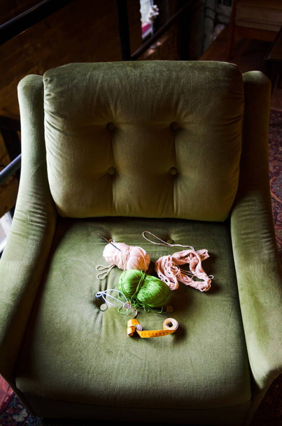 Ferramentas de crochê em uma cadeira de sofá verde
 - Foto, Imagem
