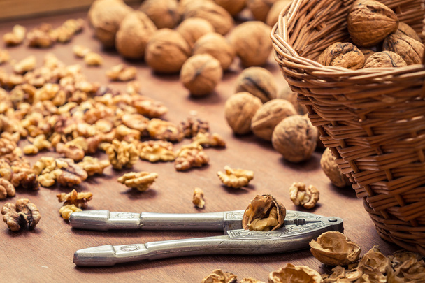 Closeup of cracking walnuts on wicker basket - Фото, изображение