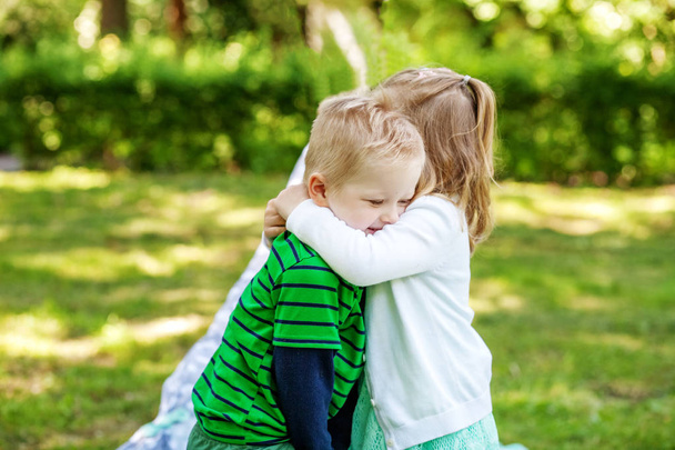 Παιδιά αγκαλιά στον κήπο. 2-3 χρόνια. Κορίτσι και αγόρι. - Φωτογραφία, εικόνα