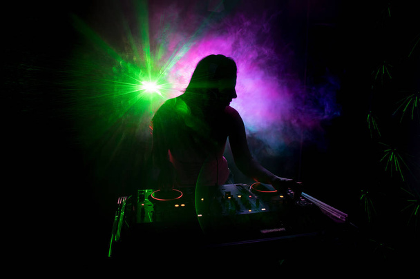 DJ spinnen, mixen en scratchen in een nachtclub, handen van dj tweaken verschillende track besturingselementen op dj's dek, strobe lights en mist, of Dj mixt de track in de discotheek op feestje - Foto, afbeelding