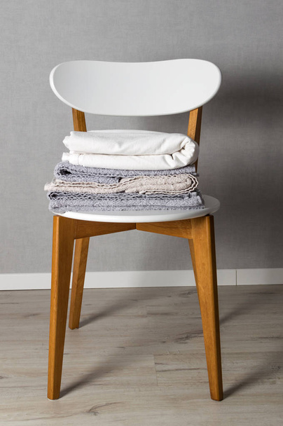 Stack of home linen on the chair in scandinavian style. Domestic cleaning - Foto, immagini
