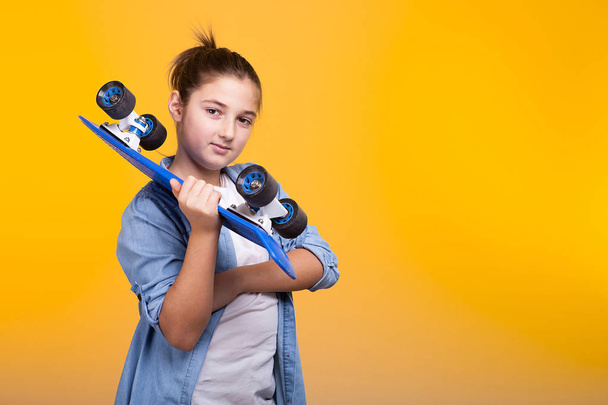 Cool teenager girl with a blue skateboard in hands - Фото, зображення