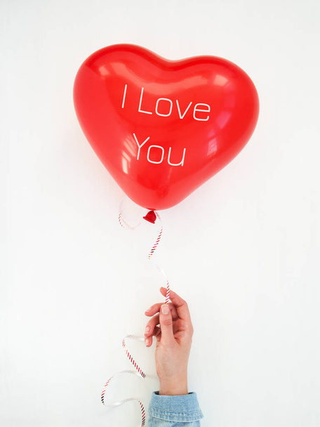Mano de mujer sosteniendo un globo Corazón Rojo con inscripción I Love
 - Foto, imagen