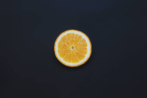Single orange fruit on black background. Slice fruit wallpaper - Foto, Imagen