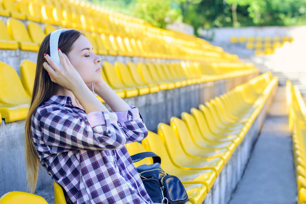 Young peaceful woman in checkered shirt listening to music at th - Photo, Image